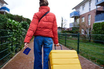 A woman walks with a yellow suitcase and a Passport of Ukraine in her hands. Ukrainian symbols. Refugees and IDPs from Ukraine 2022.