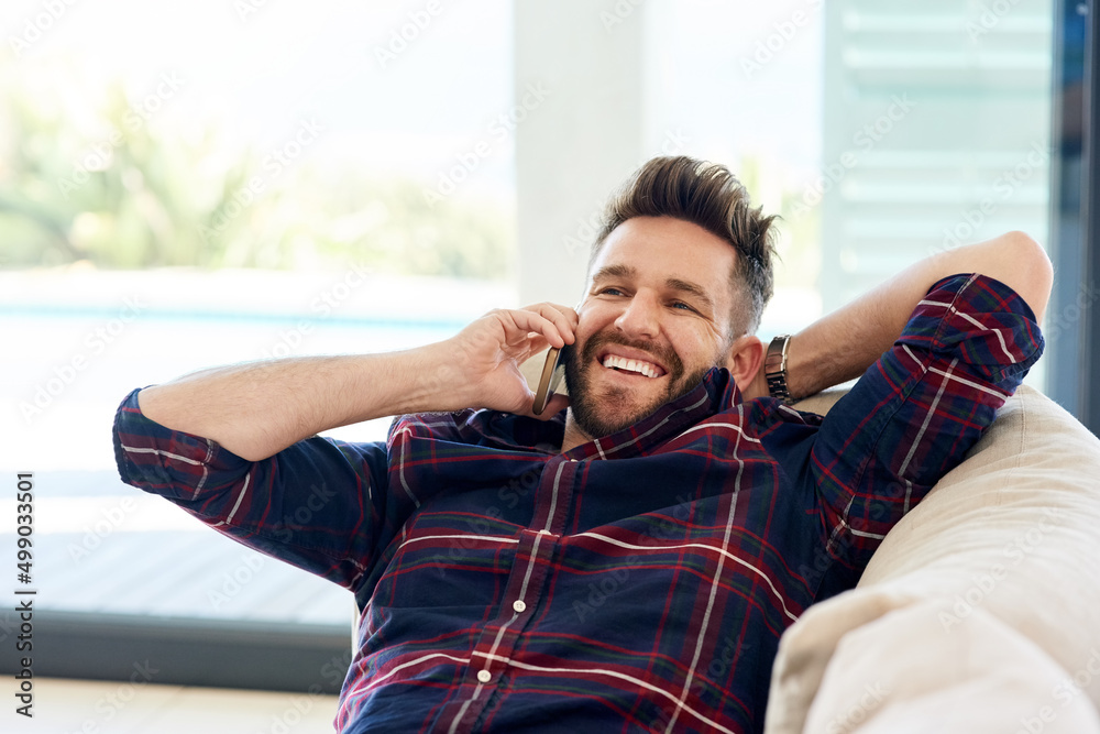 Poster wanna come over and chill. shot of a young man using his phone while relaxing on the sofa at home.