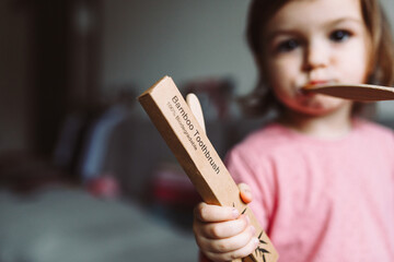 Little girl playing with wooden eco tooth brush