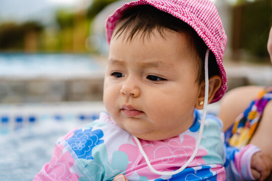 portrait of a latina baby girl at the pool in pink swimsuit