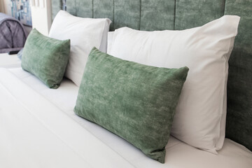 Close-up of cozy bed with light green soft pillows and headboard