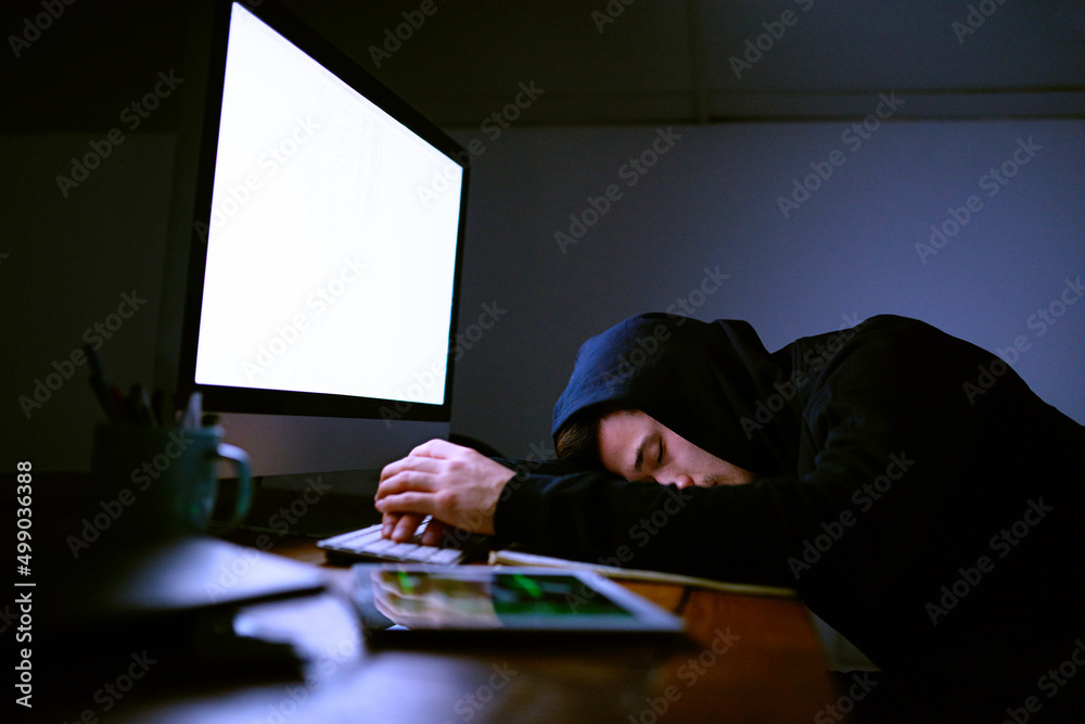 Poster falling asleep by the light of his monitor. shot of an exhausted computer programmer sleeping at his
