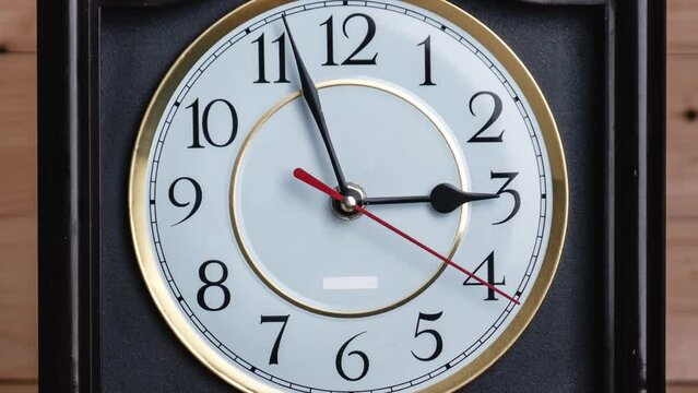 Timelapse of vintage clock with full turn of time hands at 3 am or pm on wooden background. Old Retro wall clock with white circular dial. Old-fashioned antique clock. Arrows second, minute, and hour