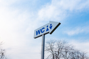 arrow shaped wc signboard on sky background, male and female public toilets icon, water closet symbol with direction for men and women