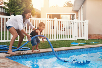 Fun times by the pool. Shot of a mother and son cleaning the pool together.