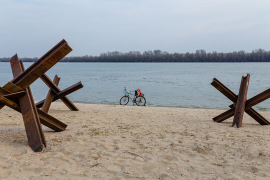 Abandoned bicycle on empty river bank with czech anti-tank hedgehoges. Interrupted life in Ukrainian cities. Russian invasion, war in Ukraine 2022