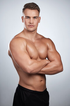 You cant fake fitness. Studio portrait of a muscular young man posing with his arms crossed against a grey background.