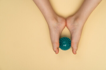 blue needle ball for massage and physiotherapy on a beige background with the image of a child's foot, the concept of prevention and treatment of hallux valgus