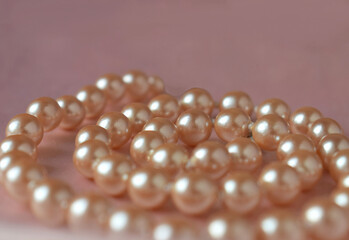 Necklace made of natural pearls on a pink background.