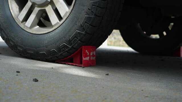 Truck tires are being chocked by tire wedges for safety.