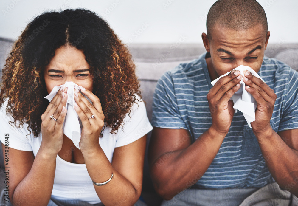 Poster they need an immune booster. shot of a young couple blowing their noses at home.