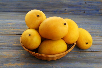 fresh ripe yellow mango fruit in basket isolated on wood background