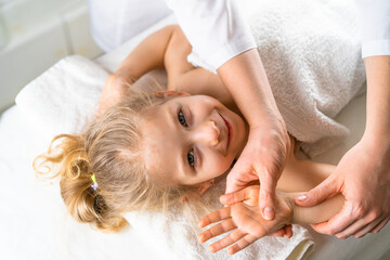 a woman gives a massage to a little girl, children's massage, prevention of scoliosis, osteopathy - obrazy, fototapety, plakaty