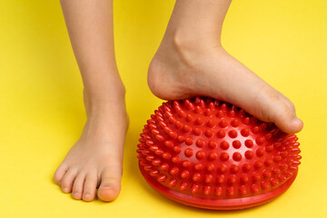 children's feet with a red balancer on a light yellow background, treatment and prevention of flat...