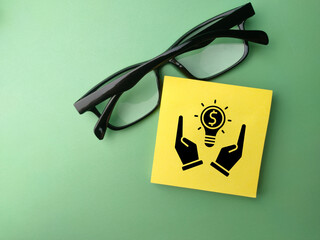 Top view glasses and sticky note with business icon on a green background. Business concept.
