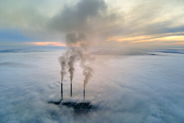 Naklejka na ściany i meble Aerial view of coal power plant high pipes with black smoke moving up polluting atmosphere at sunset