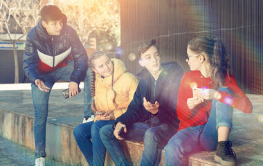 Four teenagers chatting on their smartphone on walking