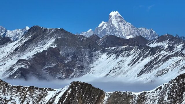 Aerial landscape of snow mountain peak of Mount Siguniang at Sichuan China snow mountain with mist floating under blue sky ,camera panning right
