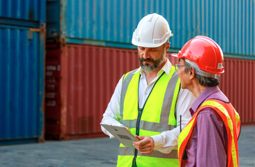 Caucasian and Asian workers teamwork men wear safety clothing. Work clothes with hard hats and use a tablet to inspect containers