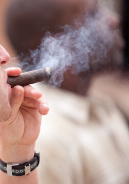 White man blowing cigar smoke into a black man's face © lindahughes