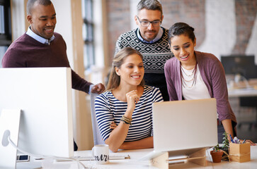 Collaborative skills are crucial in this business. Shot of a group of designers working together at a computer.