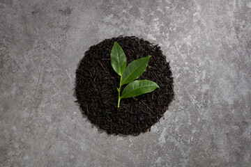 A top view of black tea decorated in wooden dish and cement background 