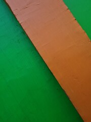 The background of the image of the building wall is green paint combined with orange paint color