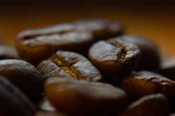 MACRO PHOTOGRAPHY OFSTACKED ROASTED COFFEE BEANS WITH WARM LIGHTING AND OUT OF FOCUS BACKGROUND