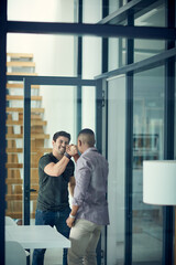 Brothers in business. Shot of two young businessmen gripping hands in solidarity in a modern office.