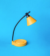 Yellow and black table lamp on a blue background.