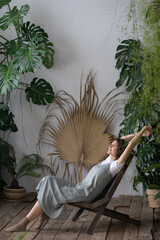 Relaxed calm woman florist rest in indoor garden breathing fresh air. Happy gardener girl enjoy...