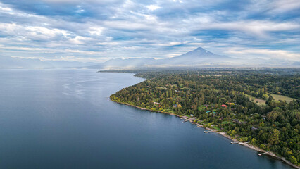 Village with a big lake and a volcano behind, docks and cabins in a cloudy day
