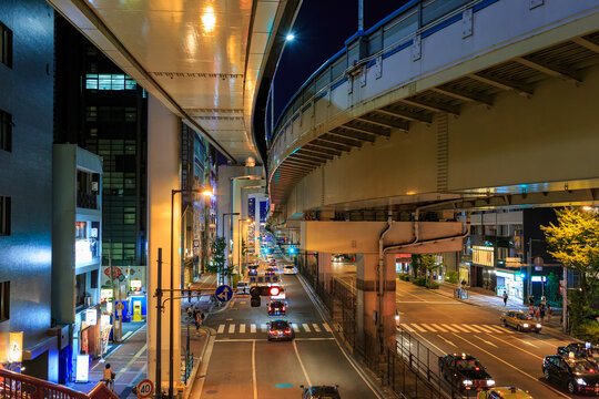 Overhead View Of Cars On Wide Road Under Elevated Tracks At Night