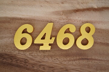 Golden Arabic numerals on a real brown and white wooden floor number 6468