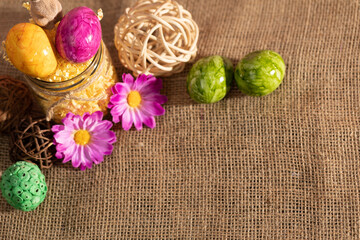 Fototapeta premium Colorful Easter eggs scattered on linen fabric as an Easter decoration.