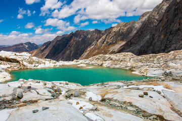 Mountainous landscape with a lagoon and blue sky with clouds in the background.