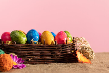Wicker basket with Easter eggs stands on linen fabric. Easter.