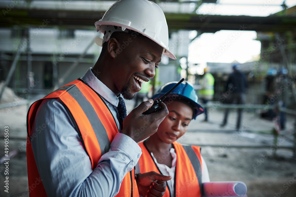 Poster quality construction inspired by teamwork. shot of a young man using a walkie talkie while working w