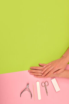 Hands with natural color manicure next to instruments for the procedure on green background