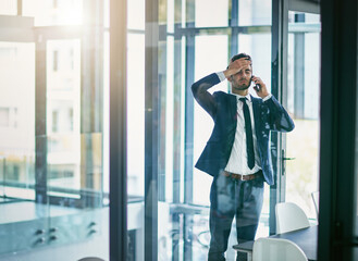 Trying hard to keep his composure. Shot of a young businessman losing his temper while talking on his cellphone.