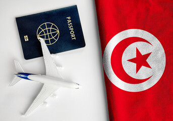 Flag of Tunisia with passport and toy airplane. Flight travel concept
