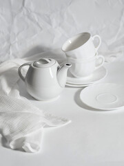 Fototapeta na wymiar minimalistic white porcelain teapot and cups for tea drinking for two