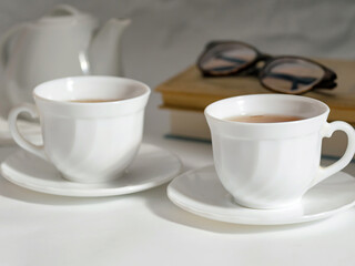 minimalistic white porcelain teapot and cups for tea drinking for two