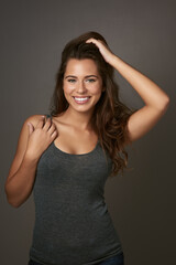 Smile away the bad hair days. Studio shot of a beautiful young woman posing against a brown background.
