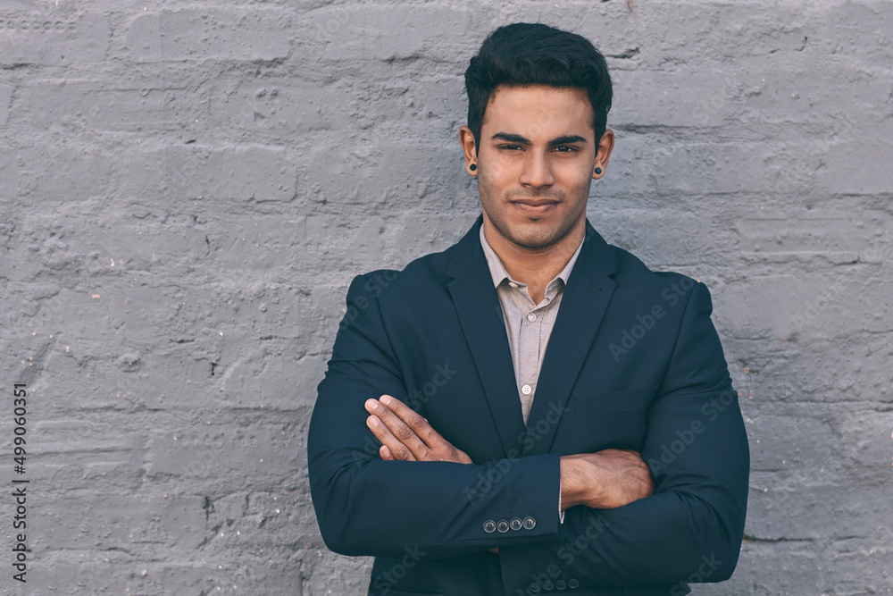 Sticker Business is what I do best. Portrait of a handsome young businessman standing against a face brick wall with his arms folded.