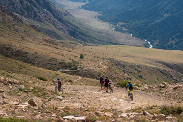 Cyclists descend on mountain gravel road. Kapalskiy vzvoz mountain pass. Way to Burkhan-bulak...