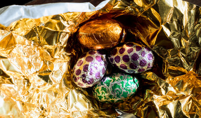 Easter eggs wrapped with aluminum foil on a gold-colored material