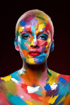 Adding colour makes all the difference. Studio shot of a young woman posing with multi-coloured paint on her face.