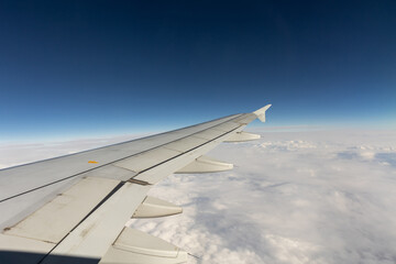 Passenger airplane wing against blue sky and clouds