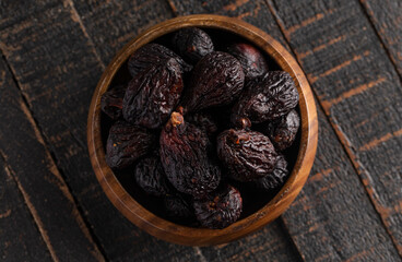 A Bowl of Dark Dried Mission Figs on a Wood Table